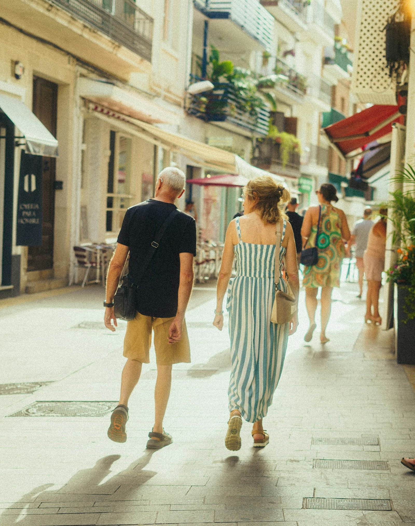 Family walking a sunlit street in a Spanish coastal town