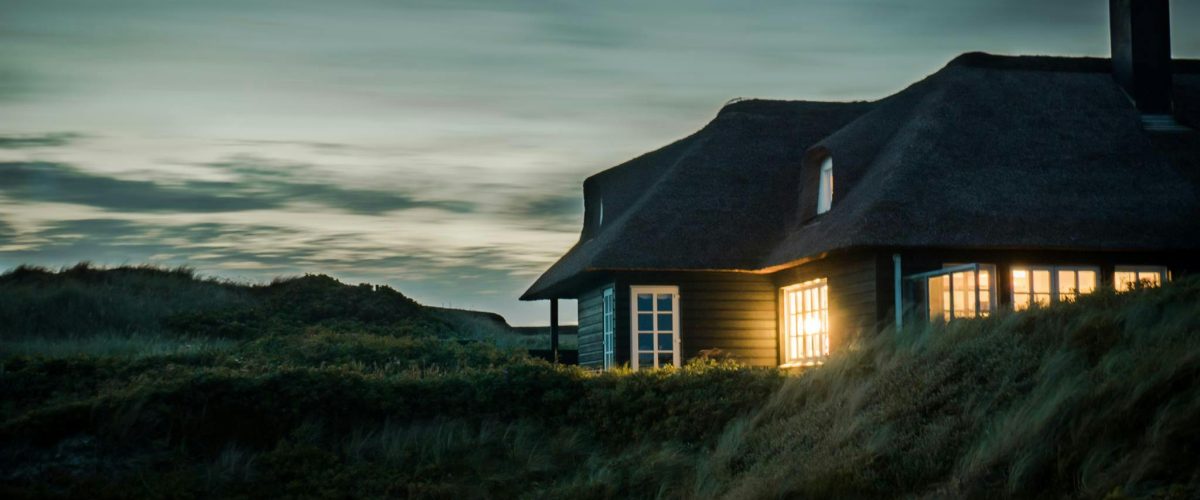 A scenic view of a cozy bungalow illuminated at dusk, nestled in lush greenery.